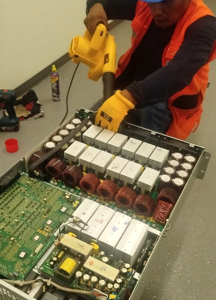 Técnico de Intelligenio limpiando un módulo de potencia de UPS Liebert durante el mantenimiento preventivo