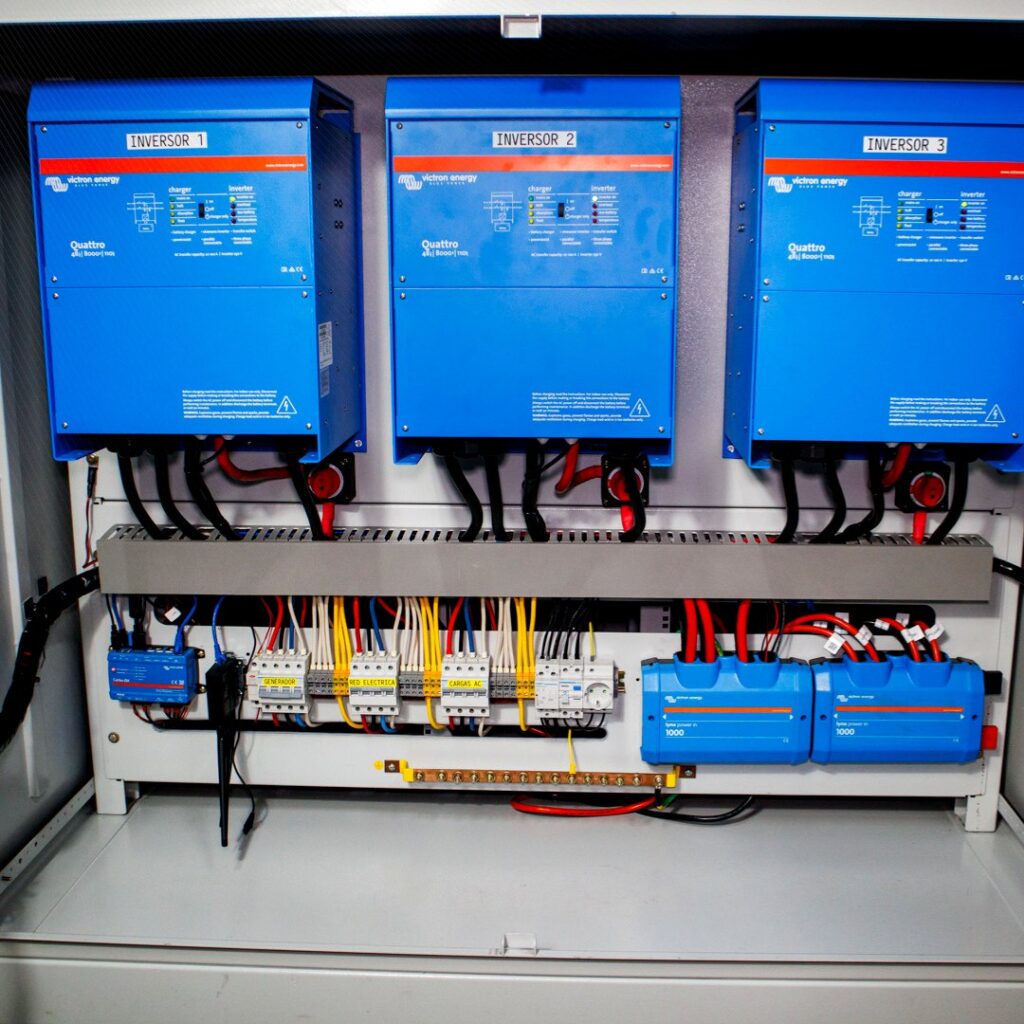 Tres inversores/cargadores Victron Energy en configuración trifásica y tablero de protecciones del PowerCube